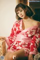 A woman in a red and white kimono sitting on a bed.