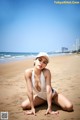 A woman in a white bathing suit sitting on a beach.