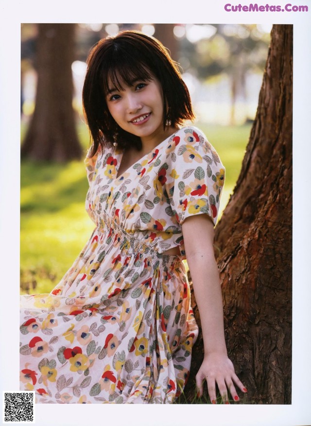 A woman leaning against a tree in a park.