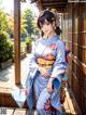 A woman in a blue kimono sitting on a wooden bench.