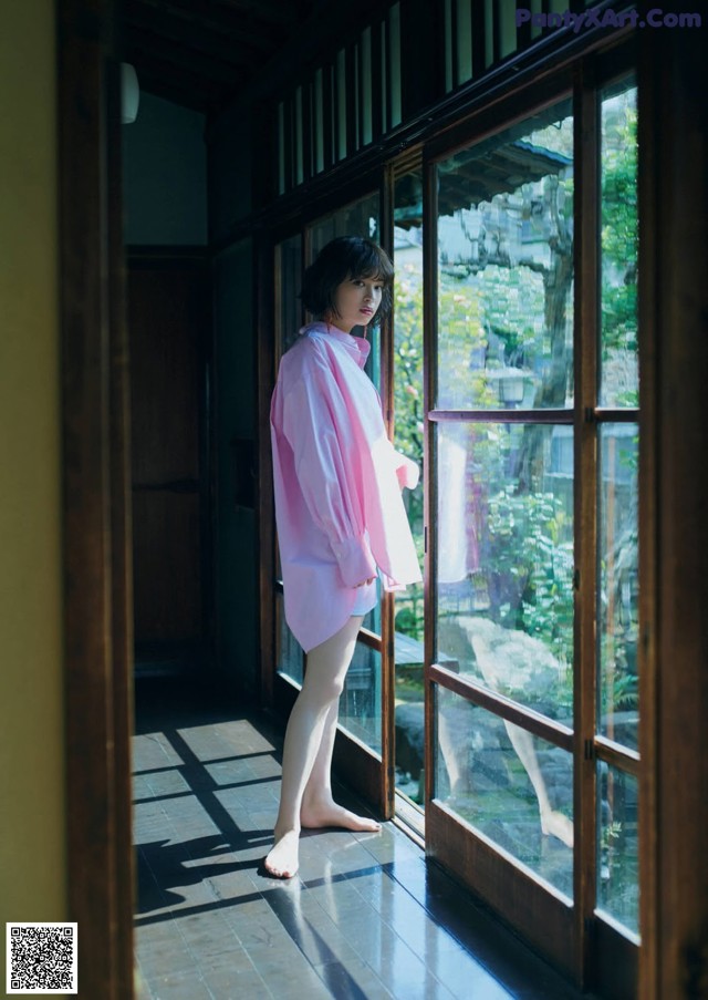 A woman standing in front of a window in a room.