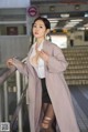 A woman in a pink coat is posing for a picture.