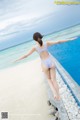 A woman in a blue swimsuit standing on the edge of a swimming pool.