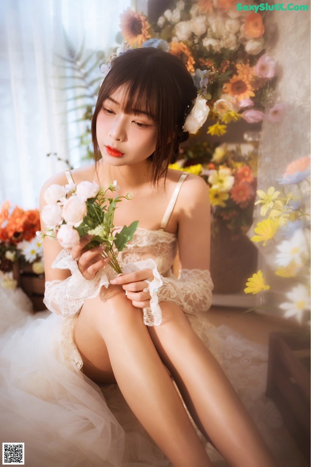 A woman sitting on the floor holding a bouquet of flowers.