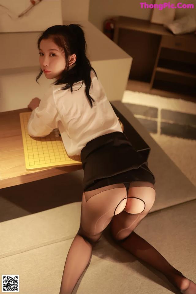 A woman in a white shirt and black skirt sitting at a desk.