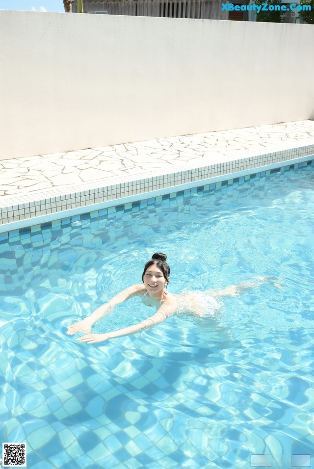 A woman floating in a swimming pool with her arms outstretched.