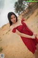 A woman in a red dress standing in the desert.