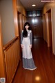 A woman in a long dress standing in a hallway.