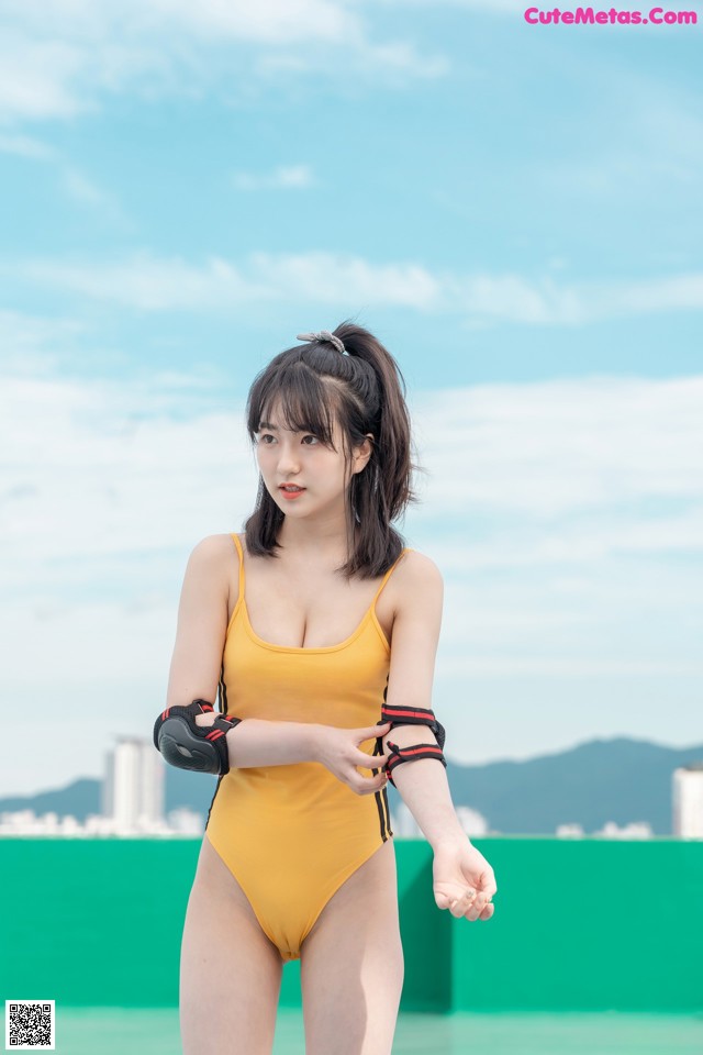 A woman in a yellow bathing suit standing on a beach.
