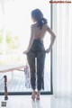 A woman in a black lingerie standing by a window.