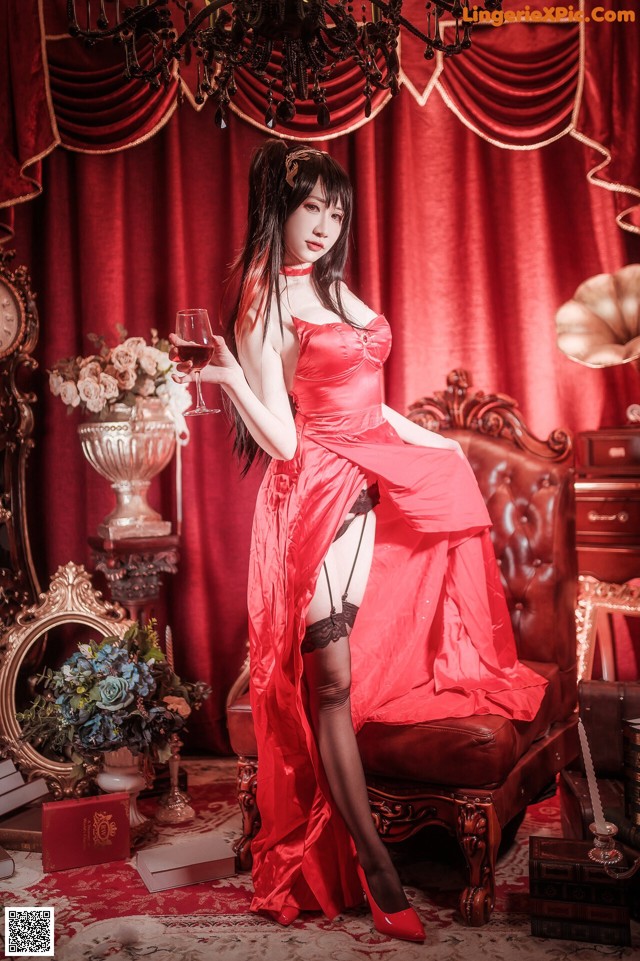 A woman in a red dress holding a glass of wine.