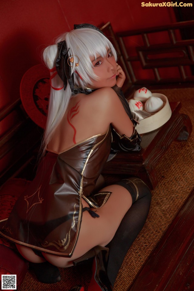 A woman in a black and gold outfit sitting on a red couch.