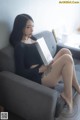 A woman sitting on a couch holding a book.