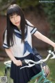 A young woman in a school uniform riding a bike.